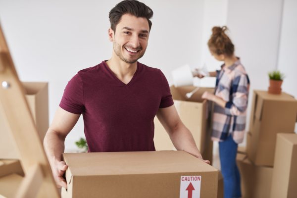 Smiling man moving into new home and unpacking his stuff